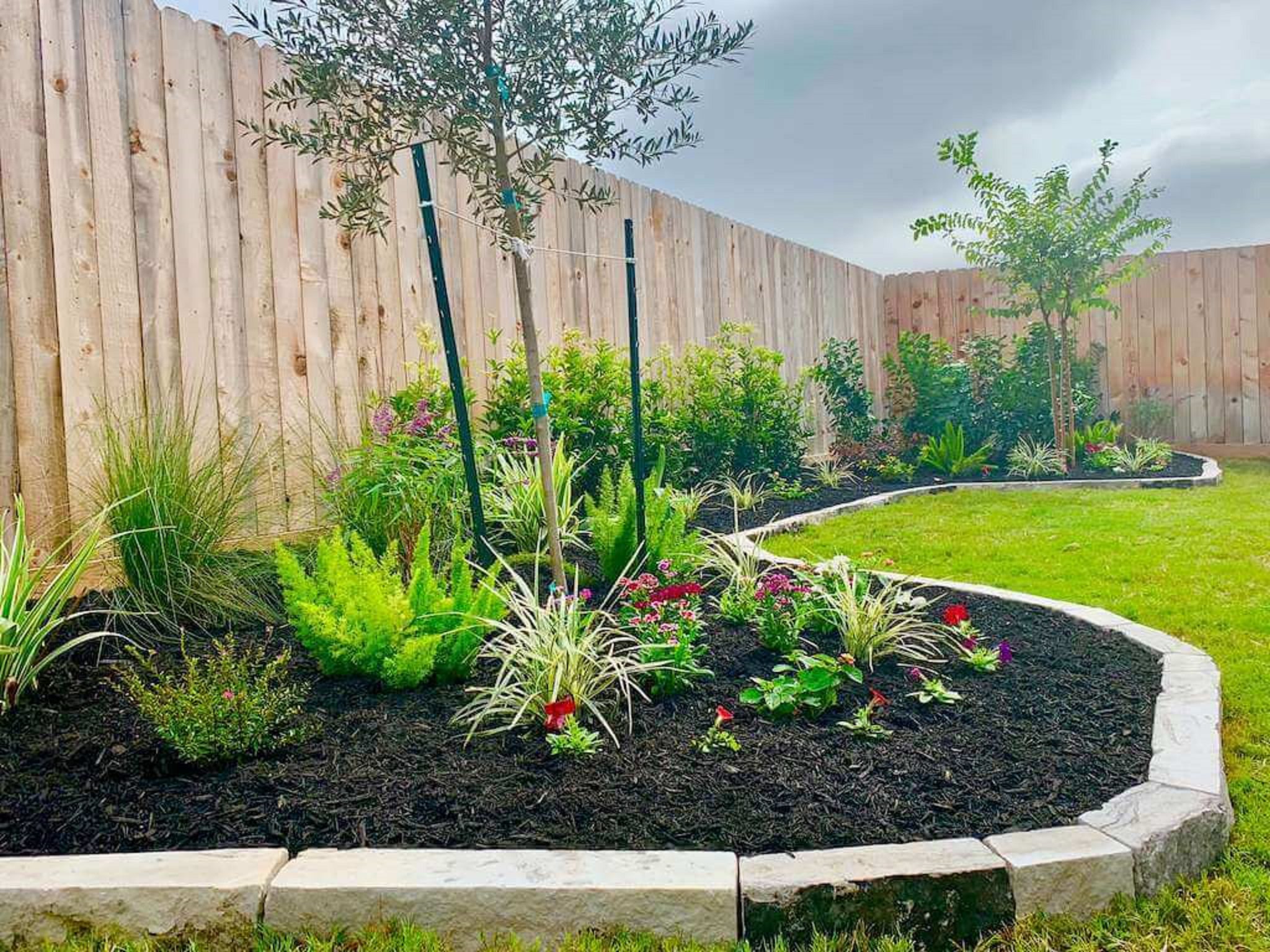 Clean flower bed with stone edging and mulch after weed control by Grow Green Weed Control